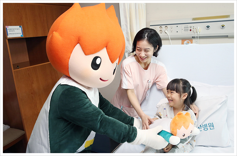 아루미가 서울아산병원 어린이병원에 입원한 환아에게 아루미 캐릭터 베개를 선물하고 있다.